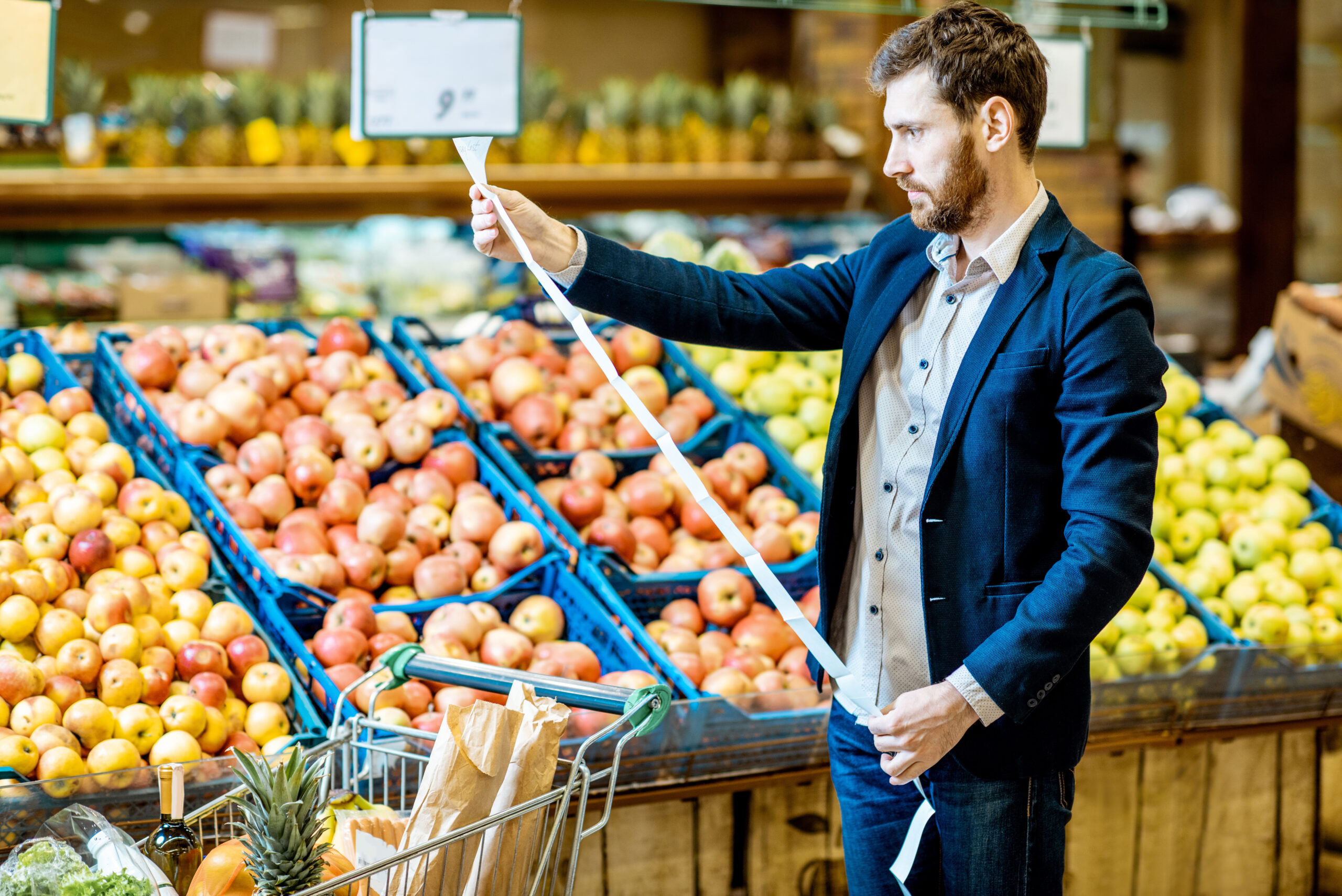 Hombre leyendo la factura en el mercado y viendo el aumento de precios: impacto de la inflación en el ahorro familiar